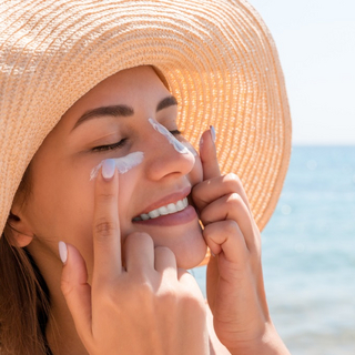 Nahaufnahme einer Frau am Strand, die sich Sonnencreme ins Gesicht schmiert