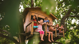 Eine Gruppe kleiner Kinder sitzt in einem Baumhaus