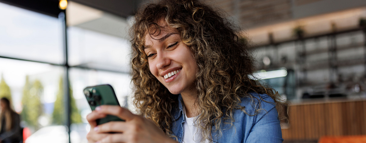 Junge lächelnde Frau mit Handy in der Hand