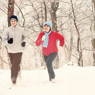 Junger Mann und ältere Frau joggen im Schnee