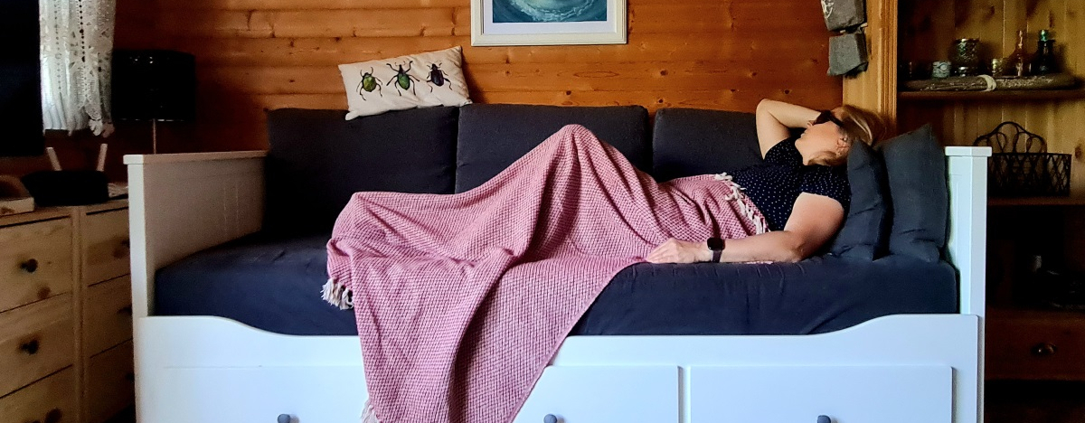 ME CFS Patienten liegt mit Decke und Augenmaske auf dem Sofa