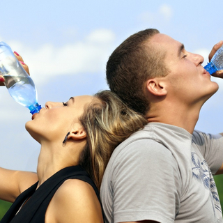 Frau und Mann kühlen sich mit Wasser trinken nach dem Sport ab