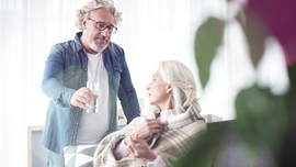 Mann reicht einer älteren Frau ein Glas Wasser