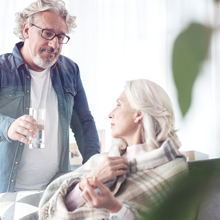 Mann reicht einer älteren Frau ein Glas Wasser