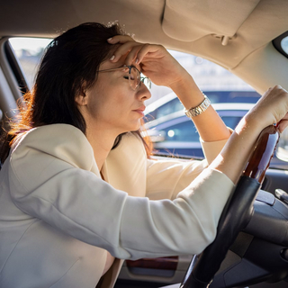 Eine gestresste Frau sitzt im Auto.