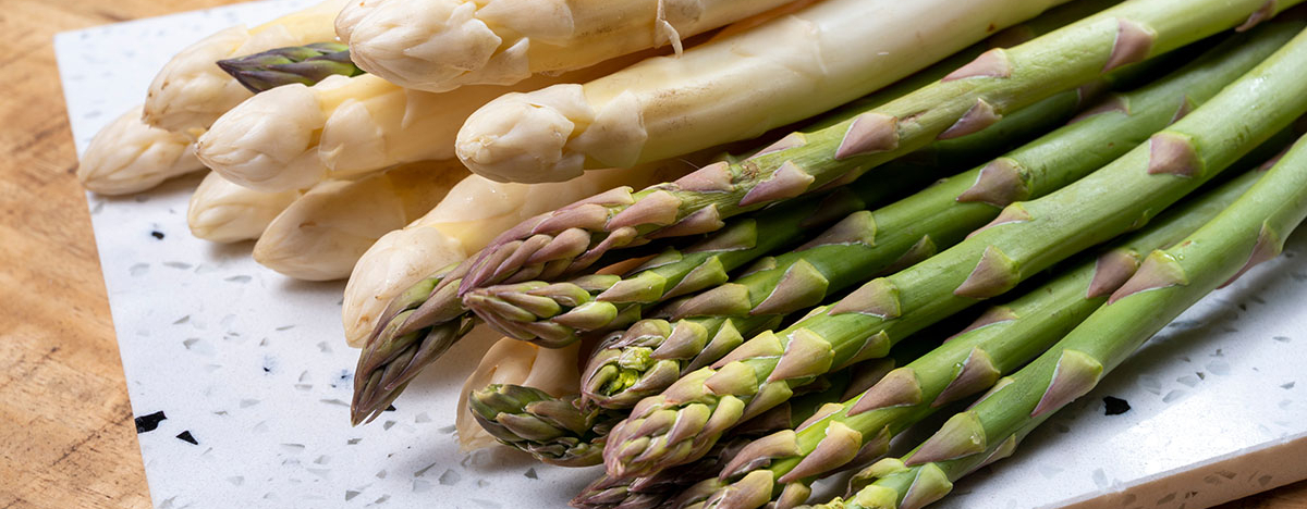 Weißer und grüner Spargel auf einem Küchenbrett