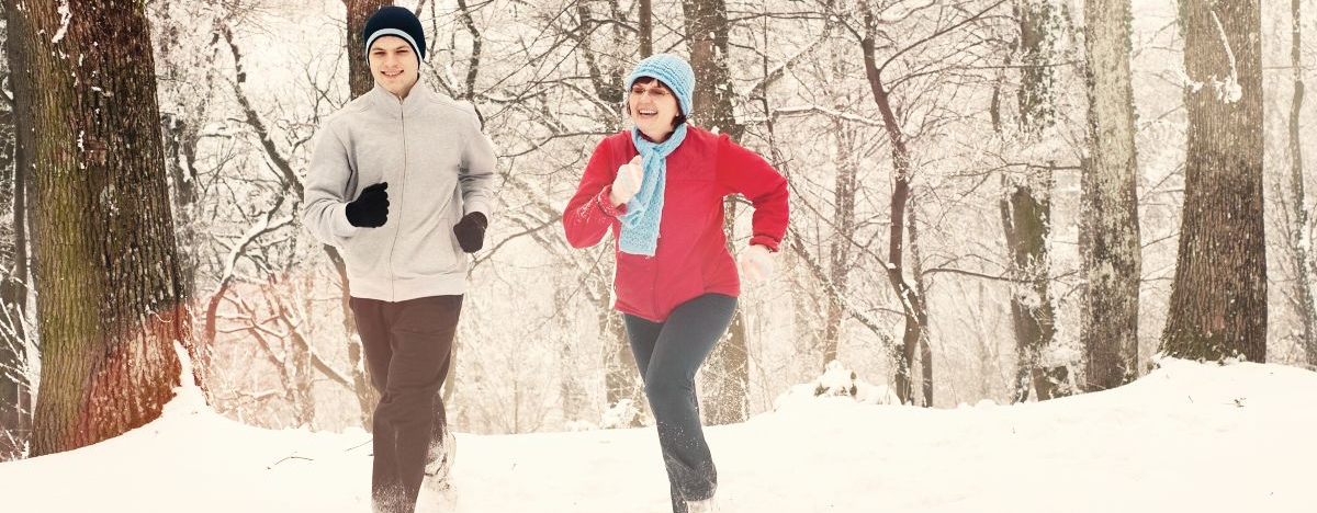 Junger Mann und ältere Frau joggen im Schnee