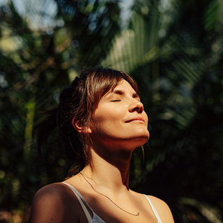 Schöne glückliche Frau genießt das Sonnenlicht im Gesicht