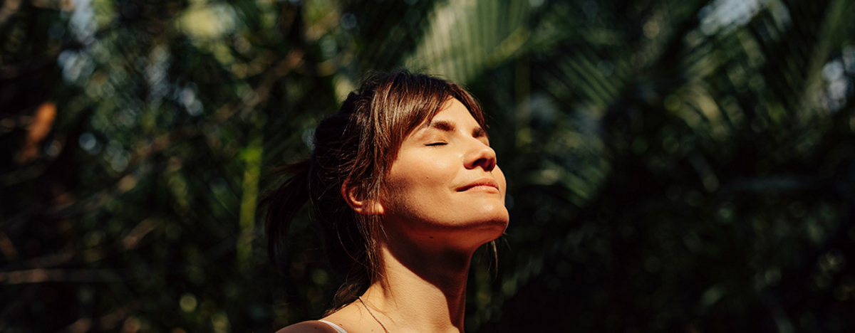 Schöne glückliche Frau genießt das Sonnenlicht im Gesicht