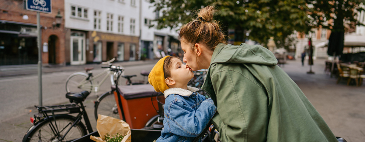 Mutter und Sohn geben sich ein Küsschen, während sie bei einem Fahrradständer stehen