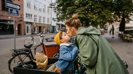 Mutter und Sohn geben sich ein Küsschen, während sie bei einem Fahrradständer stehen