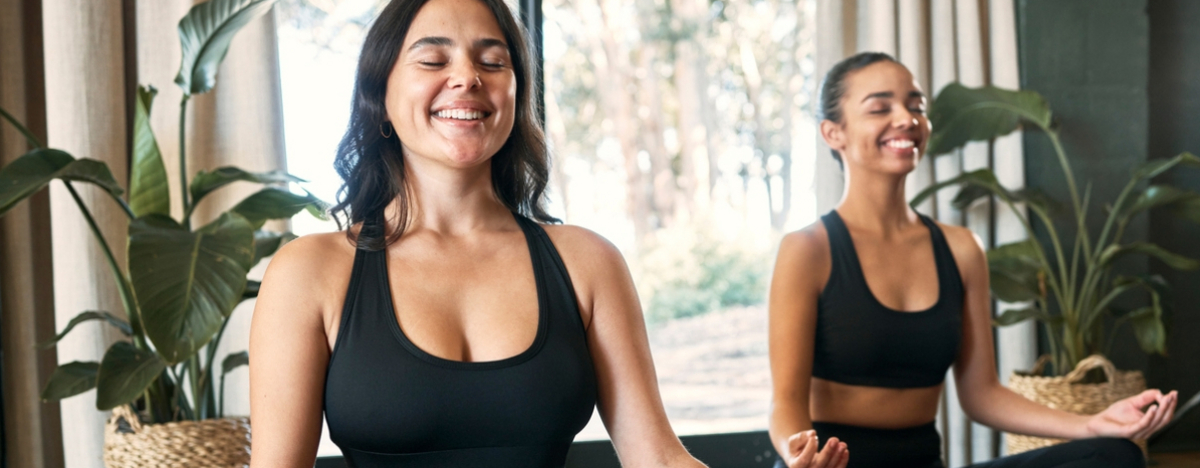 zwei Frauen lachen und machen Yoga