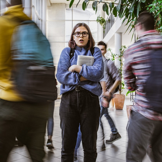 Eine Studentin mit Brille schaut ängstlich und schockiert.