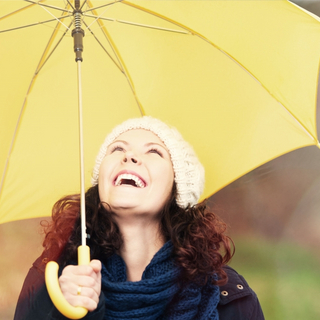 Frau ist an der frischen Luft mit einem gelben Regenschirm