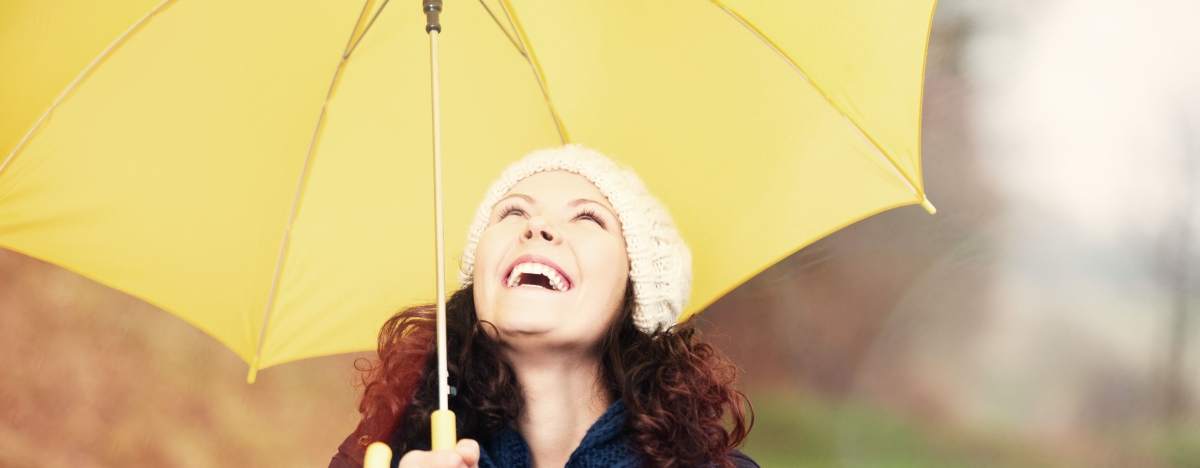 Frau ist an der frischen Luft mit einem gelben Regenschirm