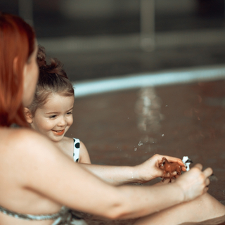 Mutter und kleines Kind spielen in einem Schwimmbecken