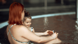 Mutter und kleines Kind spielen in einem Schwimmbecken