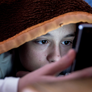 Mädchen im Bett starrt auf ihr Smartphone