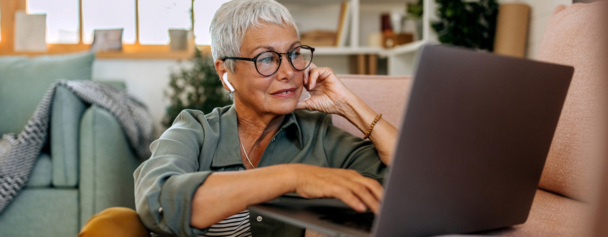 Seniorin mit Laptop auf Wohnzimmerboden