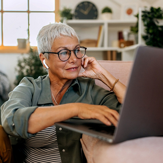 Seniorin mit Laptop auf Wohnzimmerboden