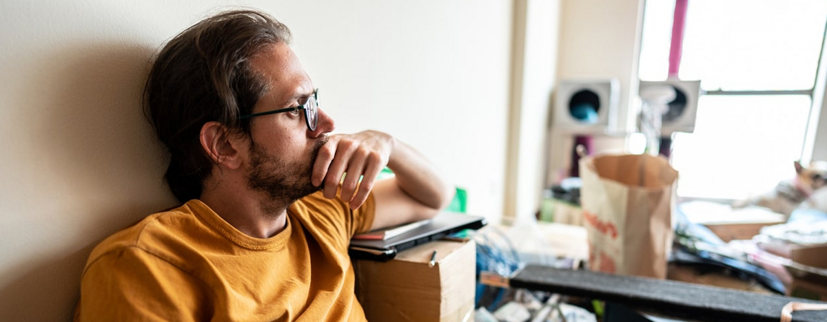 Besorgter erwachsener Mann, der zu Hause auf dem Boden sitzt