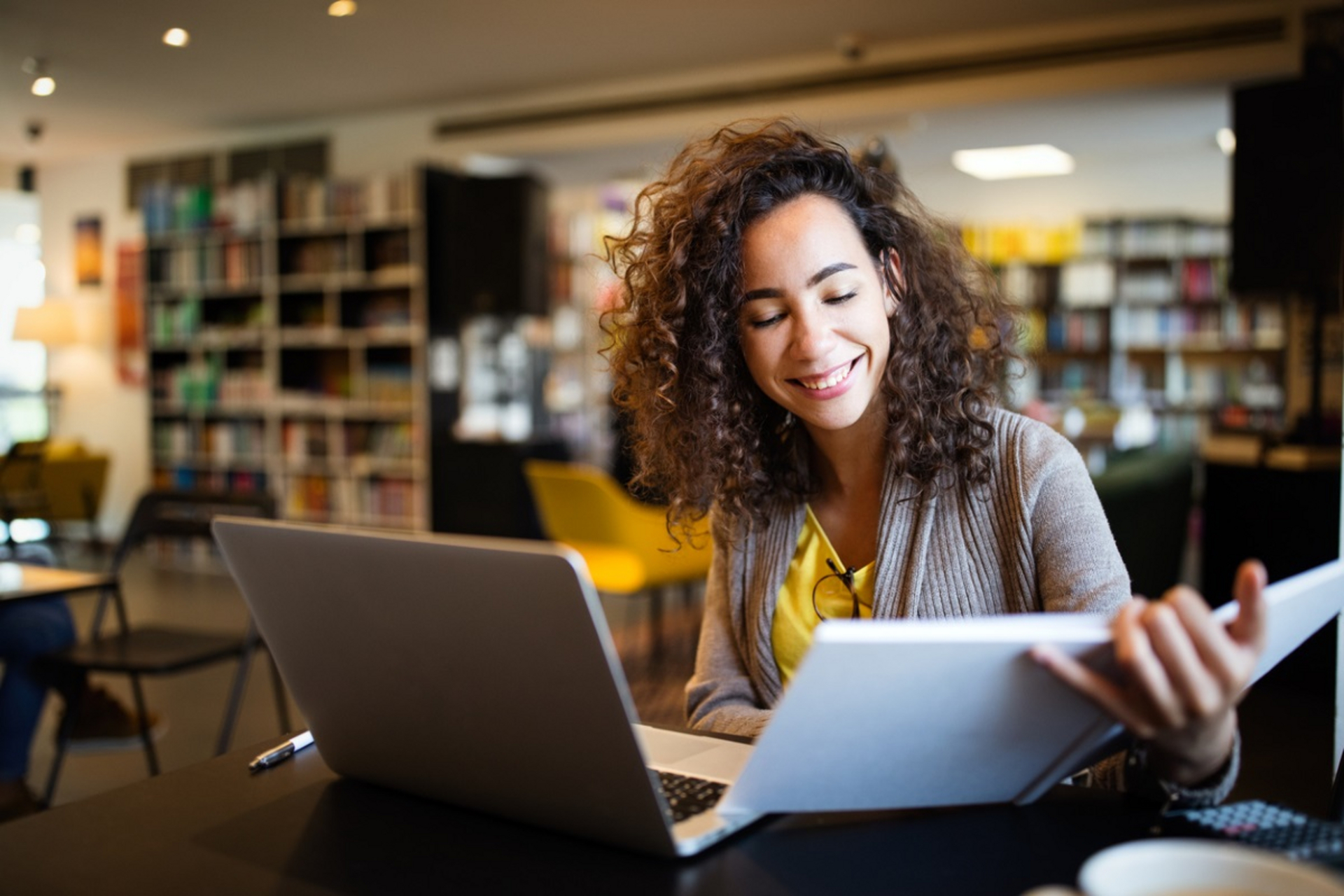 Junge Frau lernt in der Bibliothek am Laptop