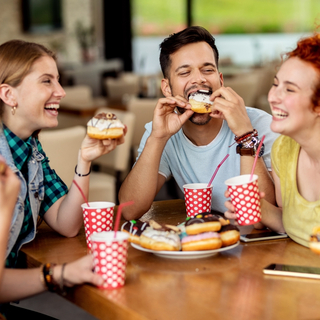 Freunde essen Donuts und lachen dabei