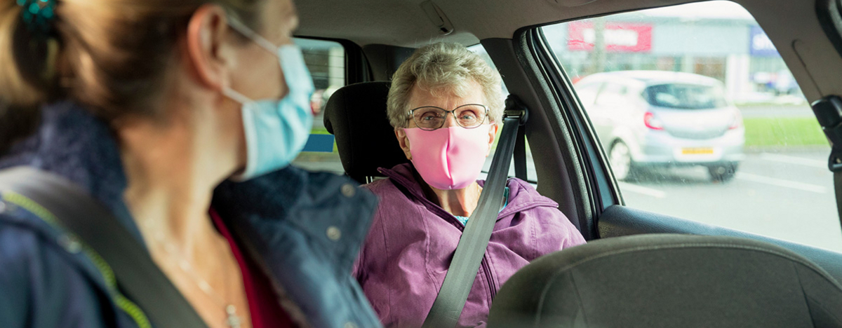 Pflegerin mit älterer Patientin im Auto