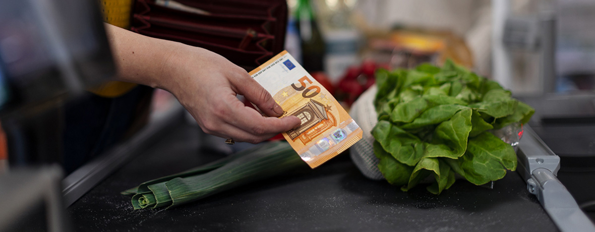 Nahaufnahme einer Frau, die an der Kasse im Supermarkt Geld gibt