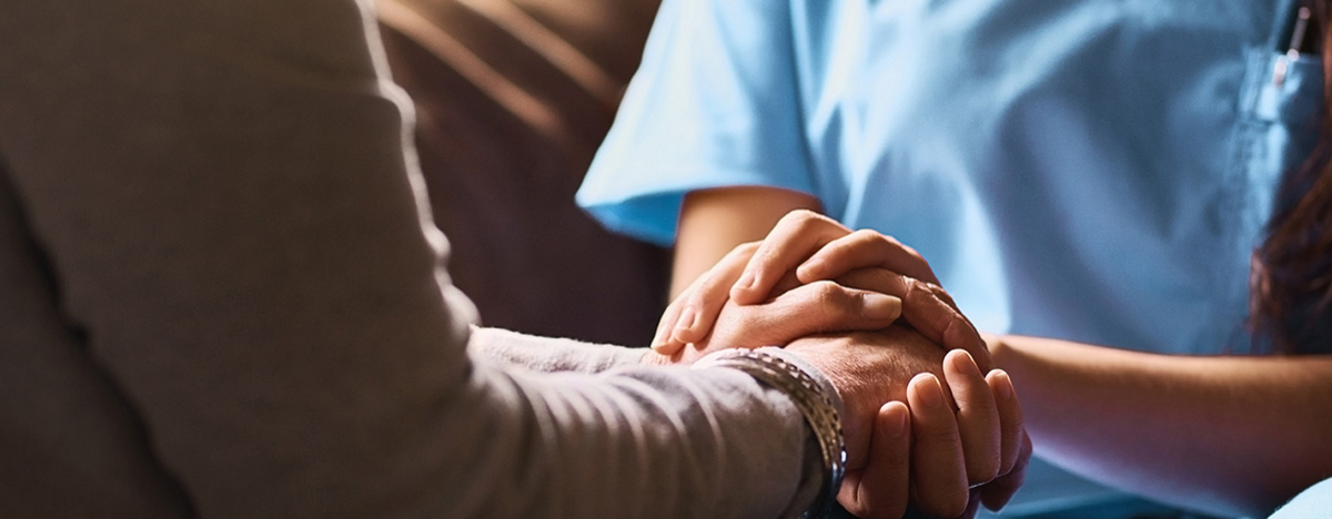 Pflegerin hält die Hand eines älteren Menschen