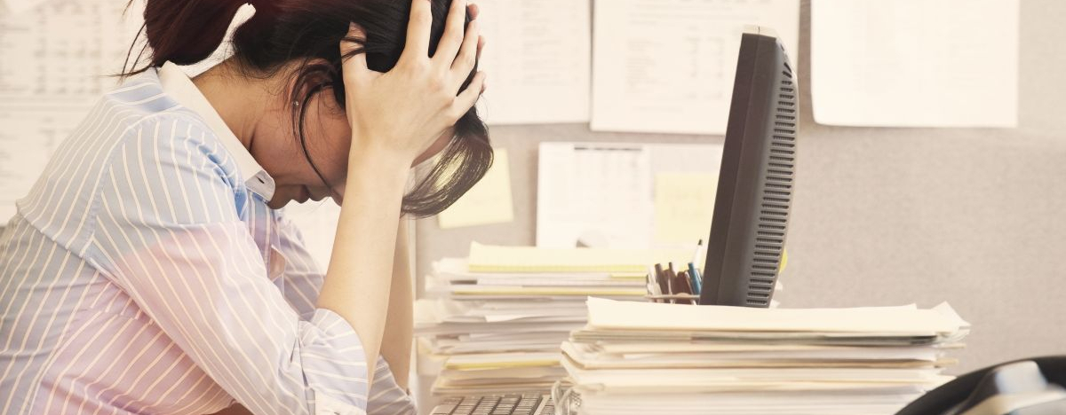 Frau im Büro schlägt vor lauter Stress die Arme über dem Kopf zusammen