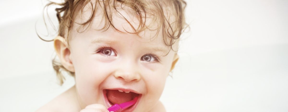 Baby sitzt in der Badewanne und putzt sich die Zähne