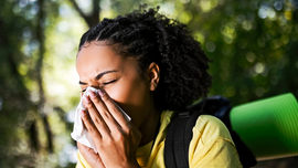 Junge Wandererin mit Allergie niest mit Taschentuch