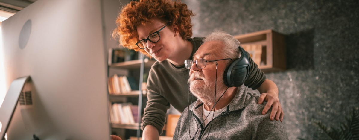 Großvater und Enkel sitzen zu Hause am Tisch und benutzen den Computer