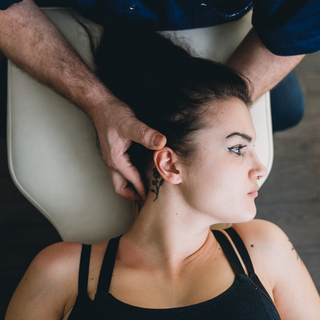 Osteopath behandelt junge Frau am Hals.