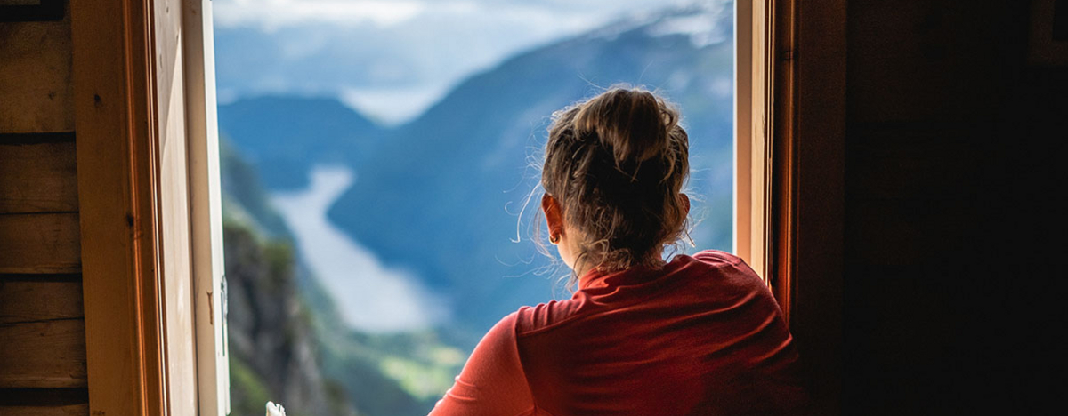 Frau mit Blick aufs Gebirge durch ein Fenster