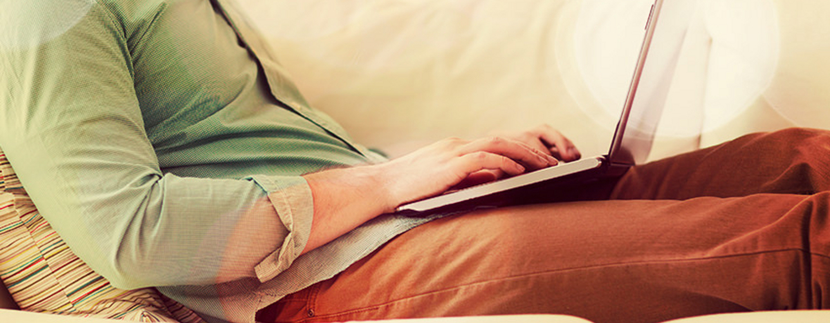 Ein Mann sitzt mit dem Notebook arbeitend auf dem Sofa