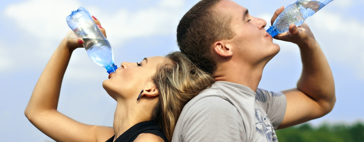 Frau und Mann kühlen sich mit Wasser trinken nach dem Sport ab