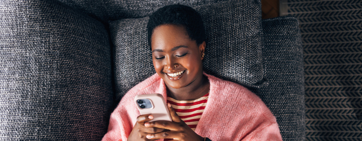 Mädchen liegt auf Sofa und sieht auf ihr Handy