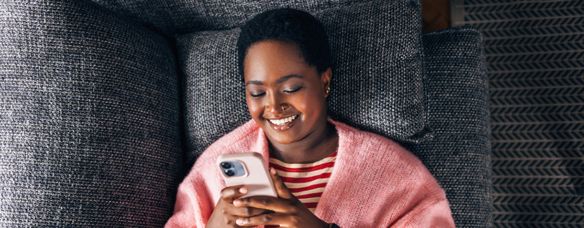 Mädchen liegt auf Sofa und sieht auf ihr Handy