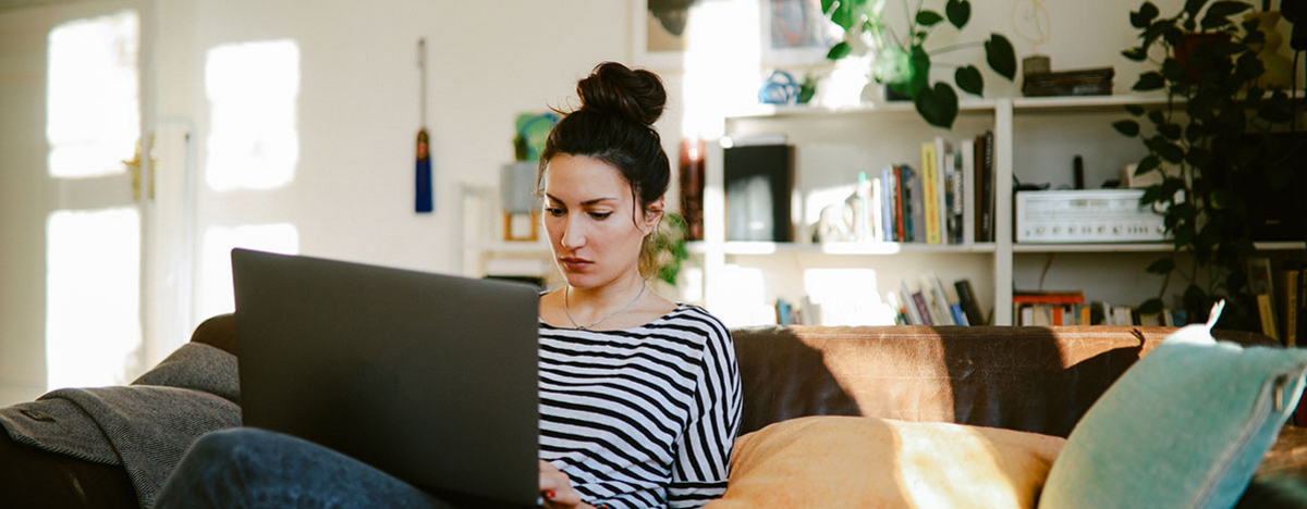 Junge Frau, die von Zuhause aus am Laptop arbeitet