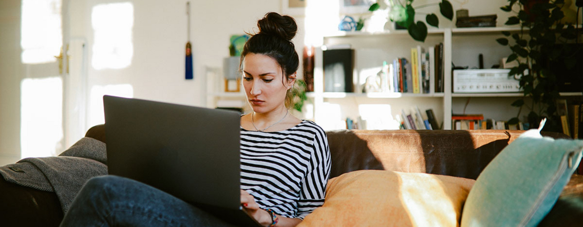 Junge Frau, die von Zuhause aus am Laptop arbeitet