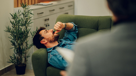 Ein depressiver Mann liegt auf einem Sofa in der Praxis eines Psychotherapeuten.