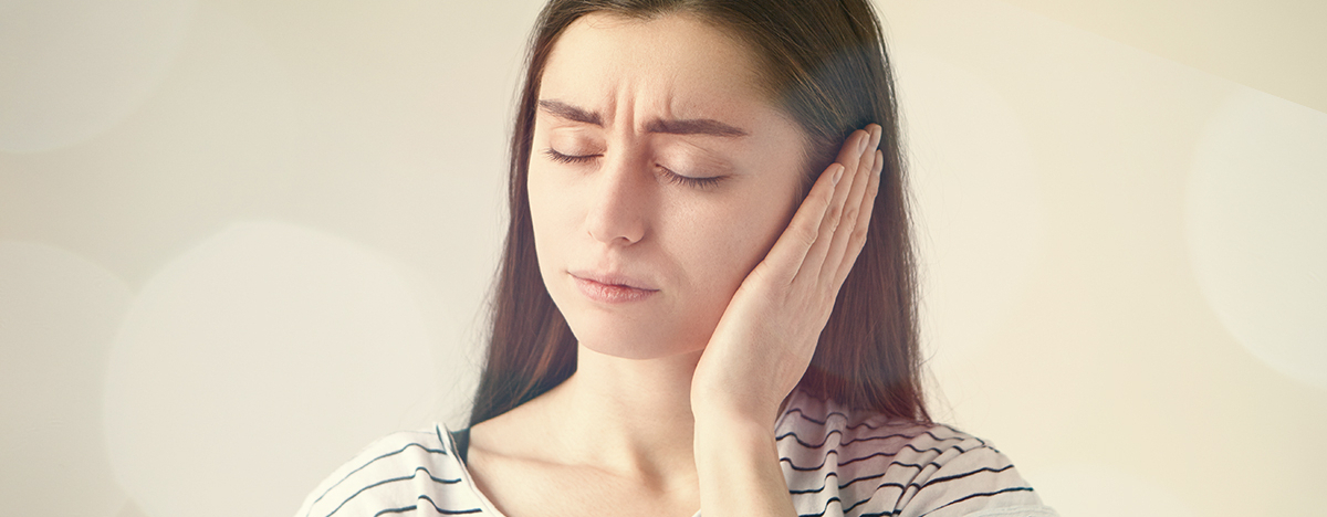 Frau hält ihre Hand ans Ohr wegen des Tinnitus