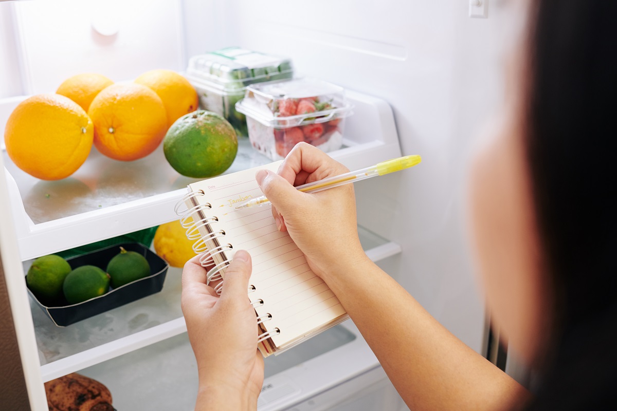 Frau am Kühlschrank mit Einkaufsliste