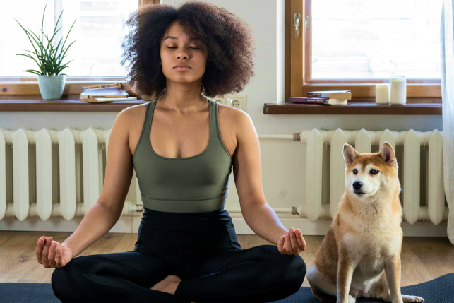 Eine Frau mit Hund meditiert.